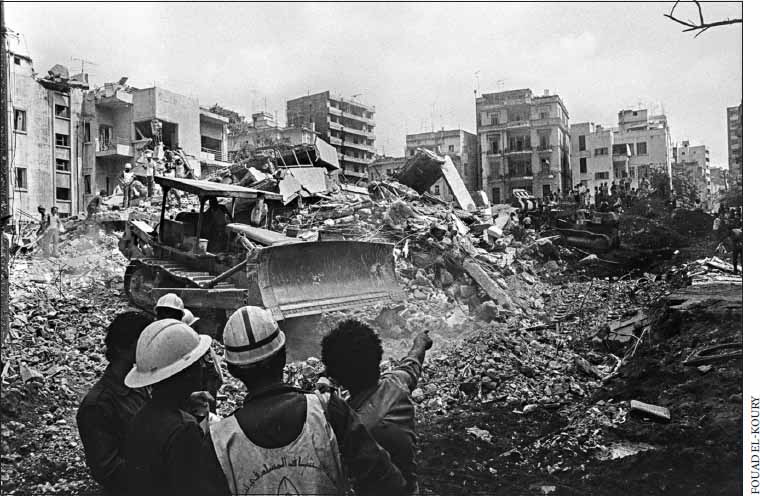 black and white photo of people pointing ahead where there is rubble and buildings some partly collapsed
