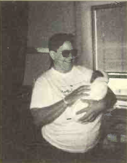 Person with sunglasses holding a baby with a big smile