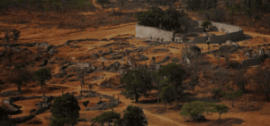 A photo from a distance showing several remnants of enclosures made of stone arranged on the landscape, with a particularly high-walled and large enclosure in the distance.